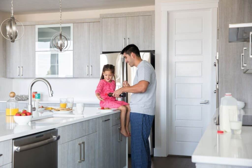 Father and daughter in modern kitchen cooking.
