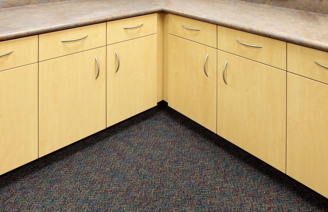 Corner kitchen cabinets with carpeted floor.