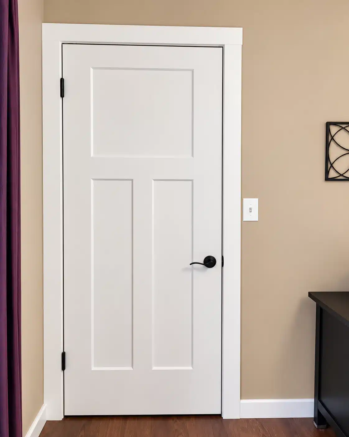 White three-panel interior door with black lever hardware, professionally installed in a West Michigan home.